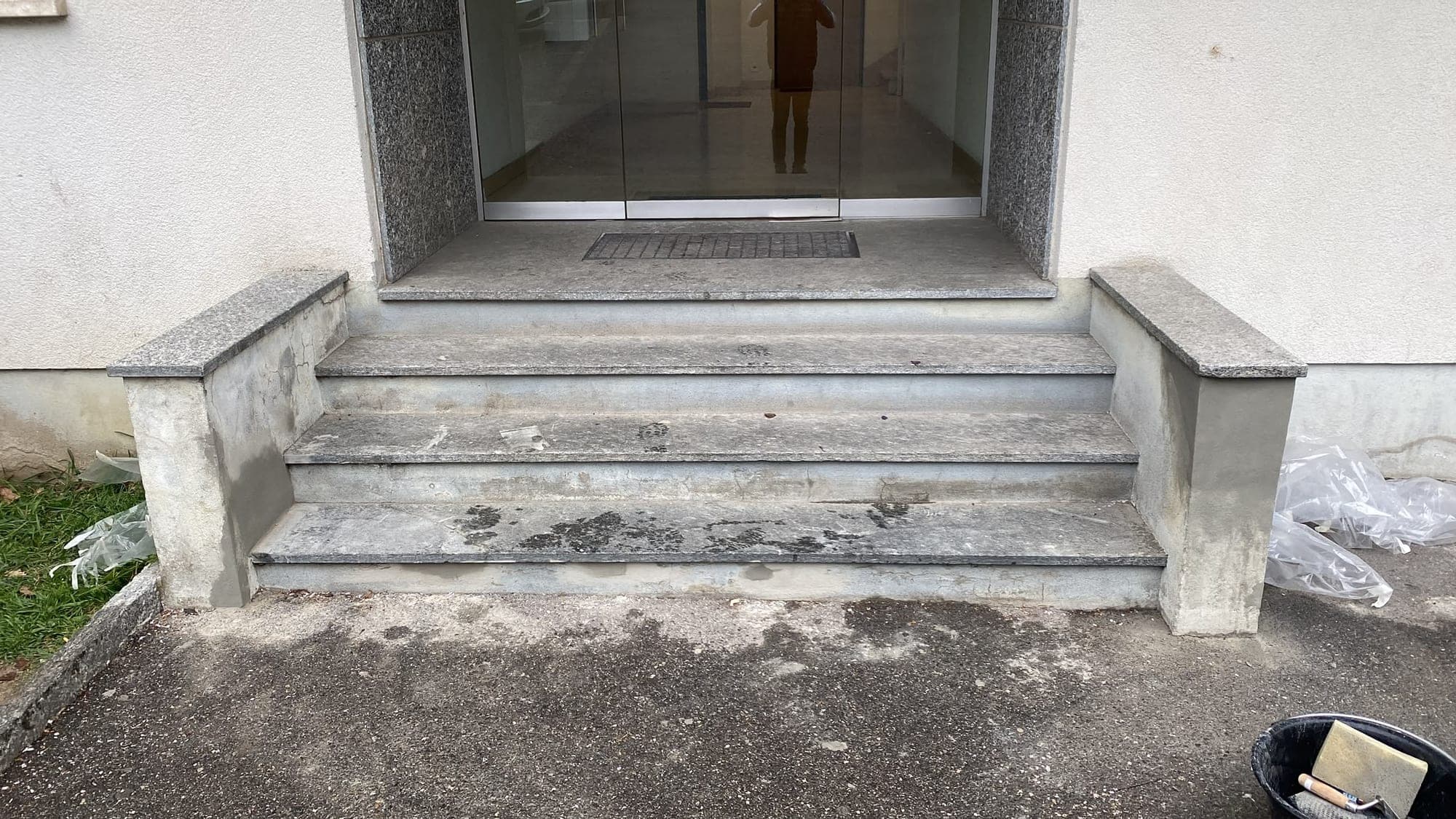Entrée d'immeuble avant travaux : marches en granit encrassées et murets au crépi éclaté