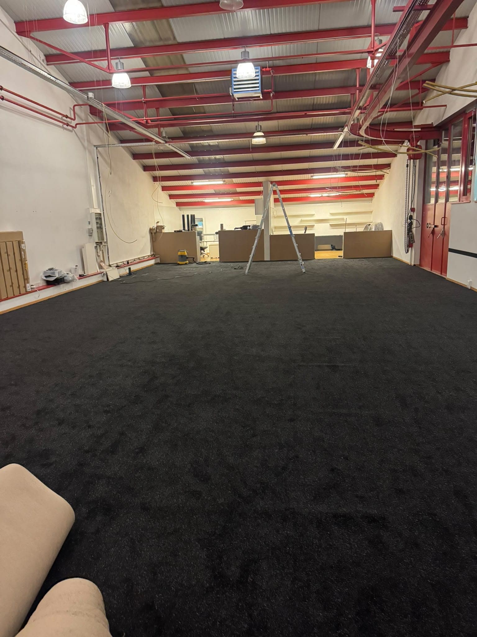 Grand local professionnel après pose d'une moquette anthracite, charpente métallique rouge
