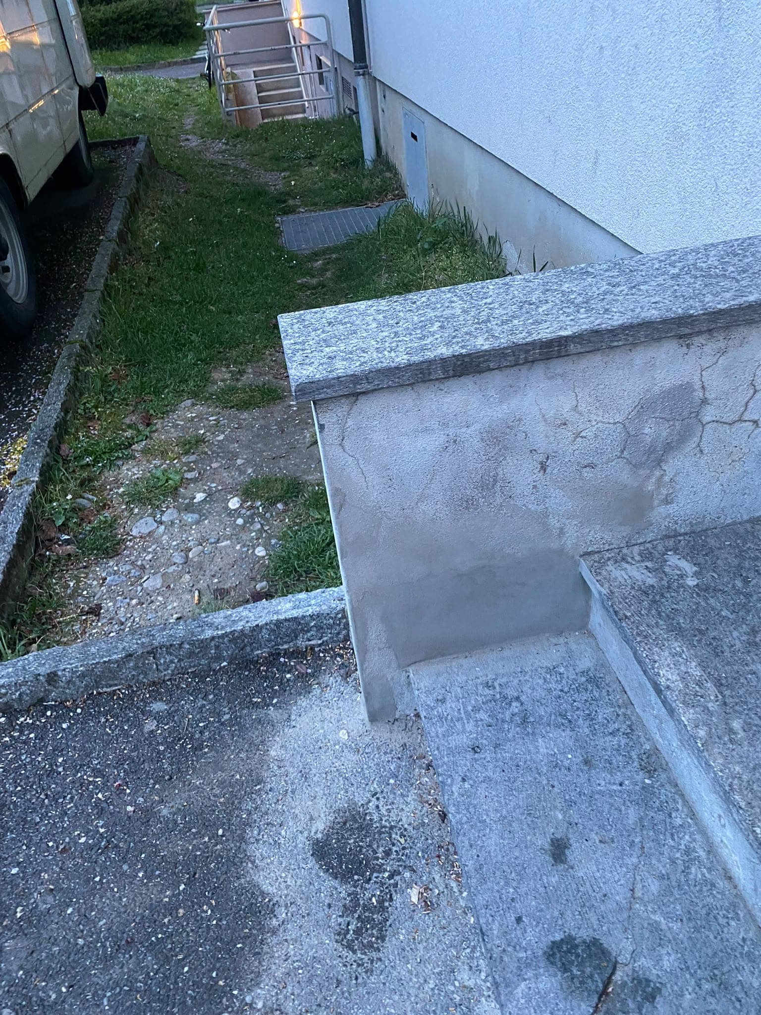 Muret d'escalier dégradé, crépi fissuré et taches d'humidité