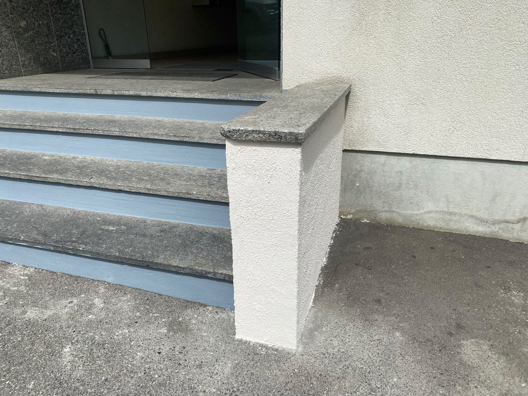 Muret et emmarchement terminés devant l'entrée vitrée d'un immeuble