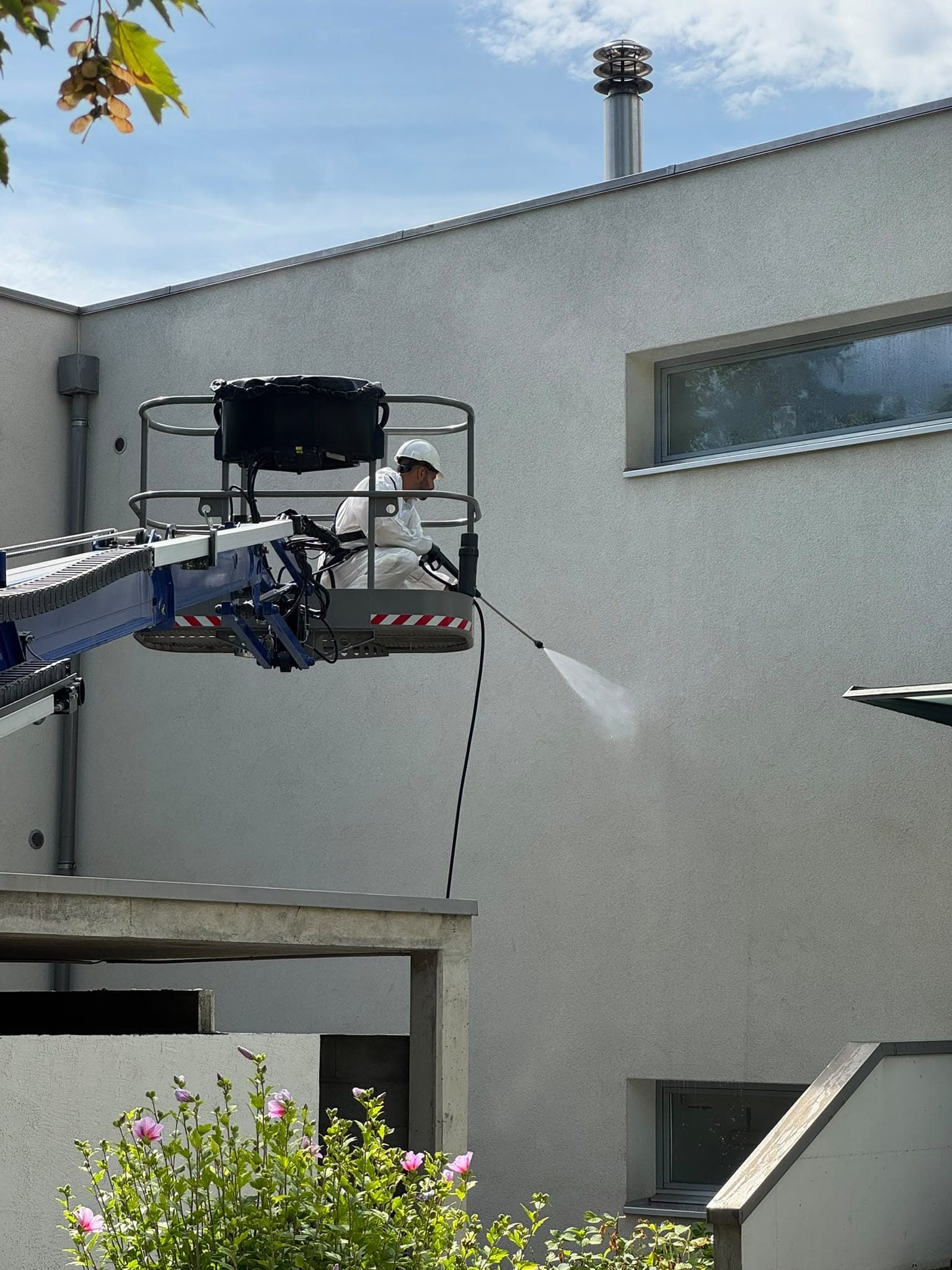 Traitement d'une façade au jet basse pression, opérateur équipé en nacelle