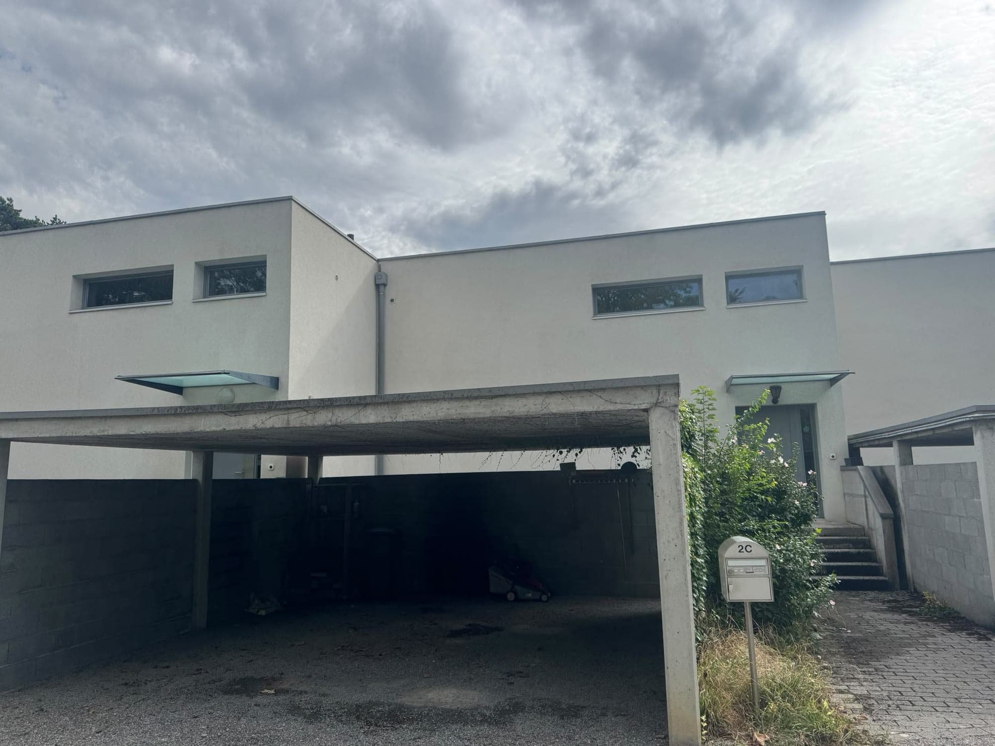 Villa contemporaine à toiture plate et carport, façade propre après traitement