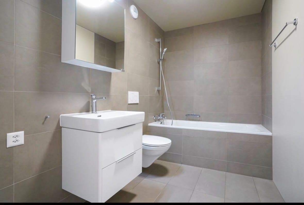 Salle de bain terminée : baignoire, meuble vasque suspendu et carrelage taupe