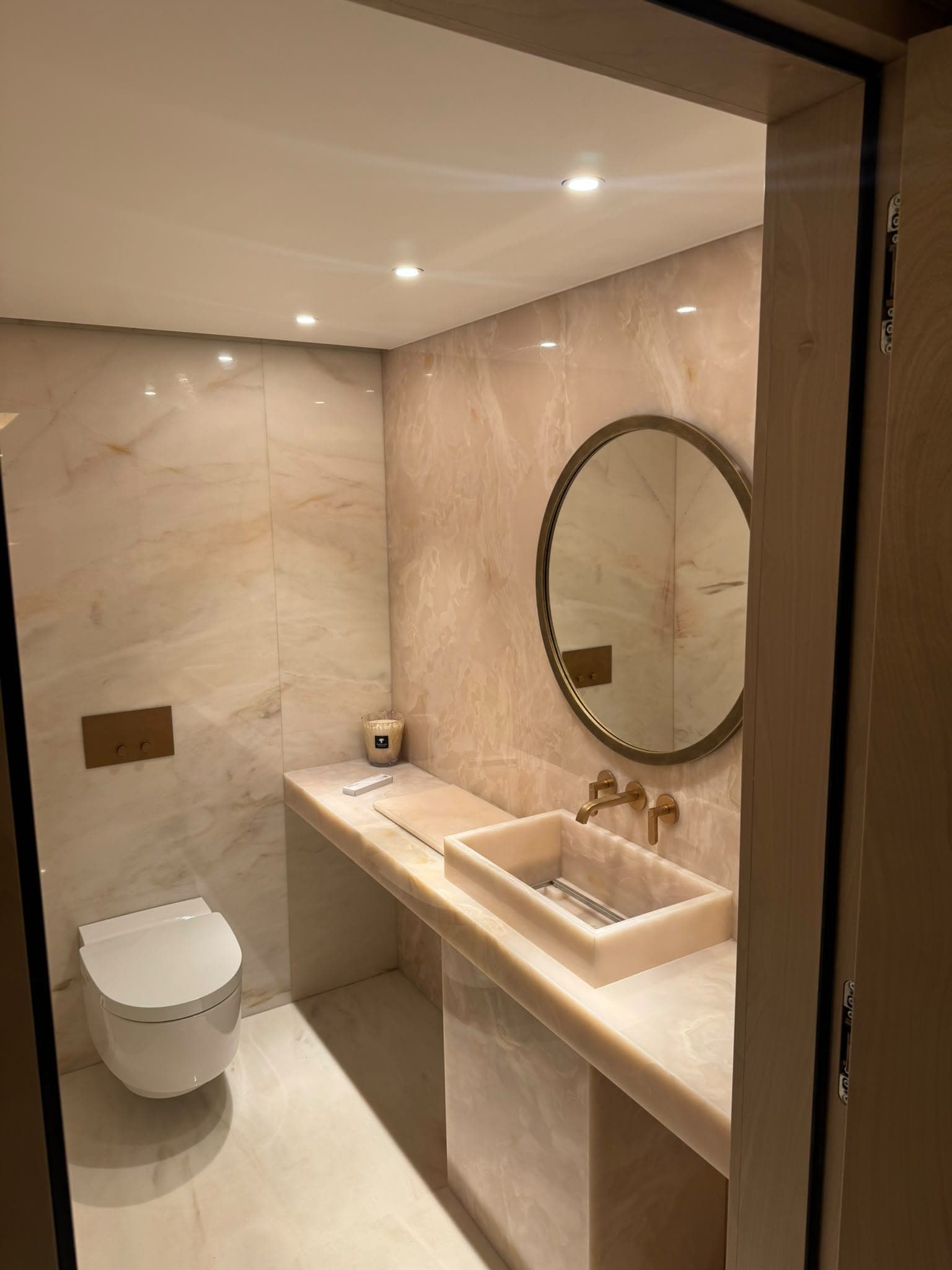 Salle d'eau haut de gamme habillée d'onyx clair, robinetterie et miroir en laiton